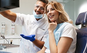 Female patient and cosmetic dentist smiling while looking at screen