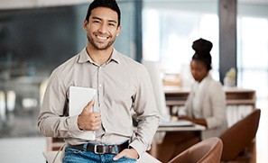 Man smiling while sitting on desk at work