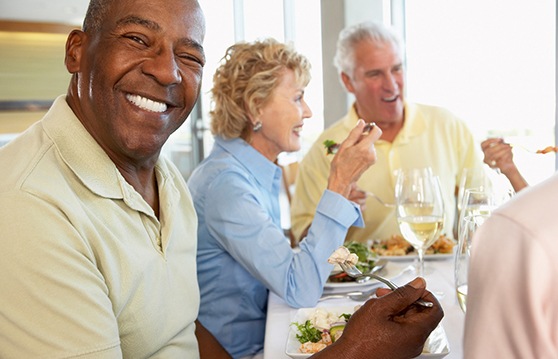 Patient in Renton with dentures smiling with friends