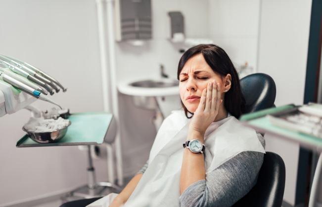 Woman holding her cheek in pain before emergency dentistry