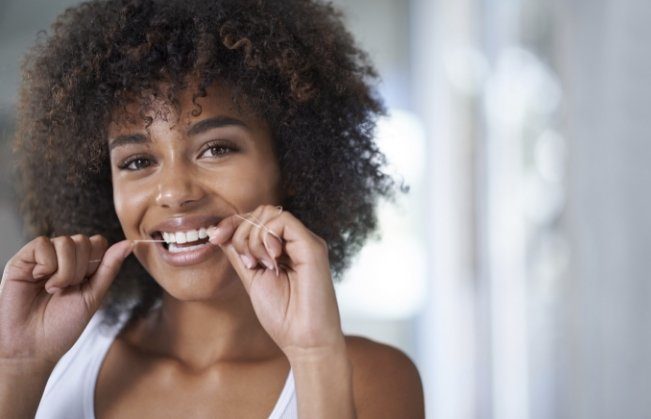 Woman flossing to prevent dental emergencies