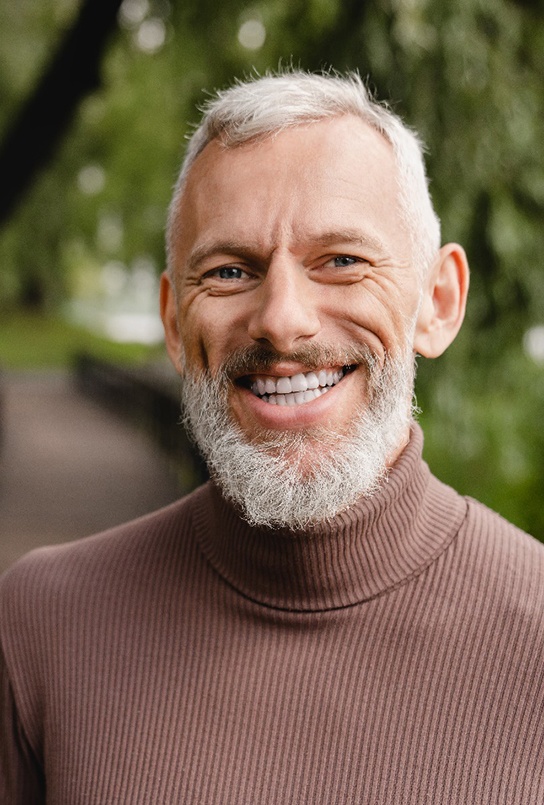 Senior bearded man standing on bridge and smiling