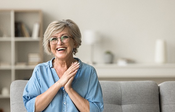 Smiling senior woman in blue button up shirt sitting on couch