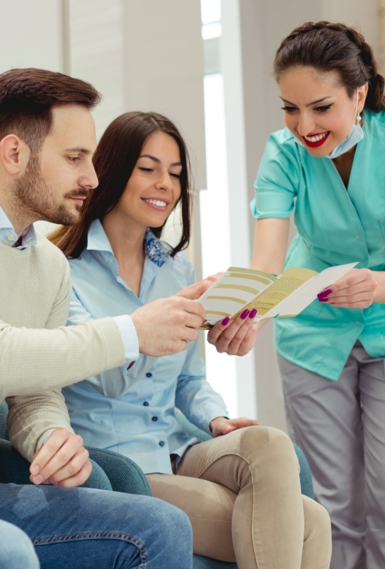 Two dental team members behind the dental office reception desk