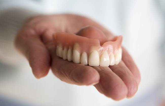 Hand holding full denture