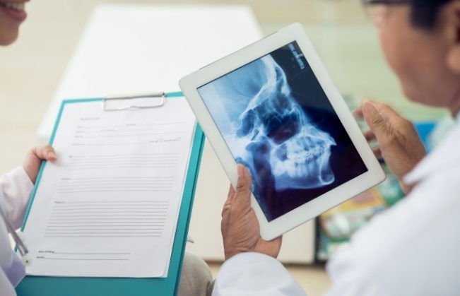 Dentists reviewing dental patient charts to provide diagnosis and T M J treatment