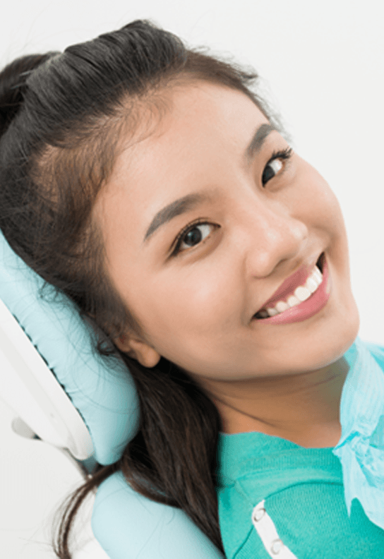 Woman sitting back in dental chair and smiling