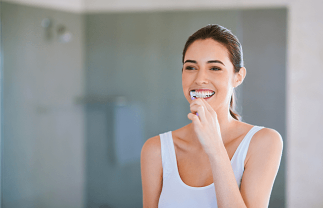 Woman brushing her teeth and smiling