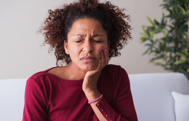 Woman with toothache sitting on couch at home