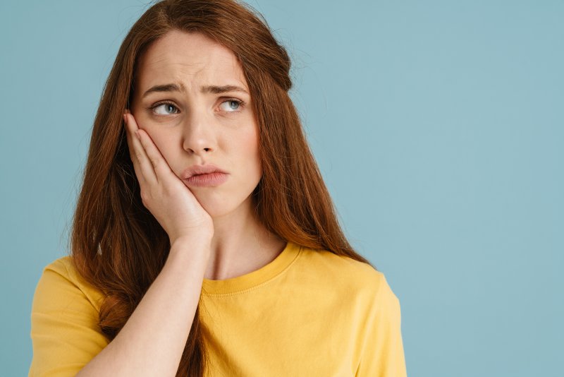 Patient holding their cheek due to a dental emergency